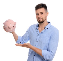 Photo of Disappointed young man with empty piggy bank on white background