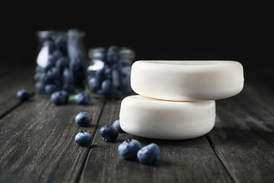 Photo of Soap bars and blueberries on wooden table