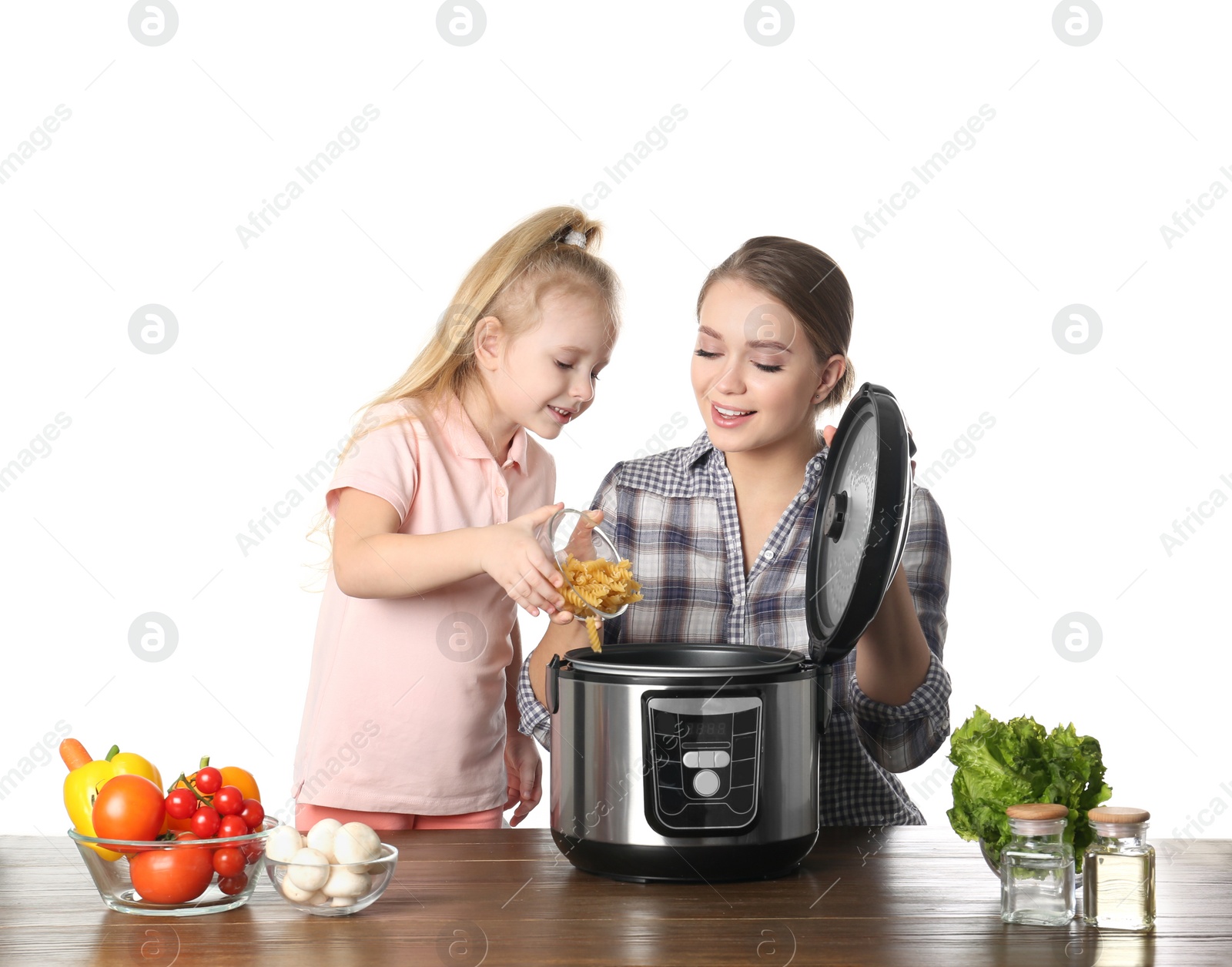 Photo of Mother and daughter preparing food with modern multi cooker at table against white background