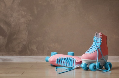 Photo of Vintage roller skates on floor near brown wall. Space for text