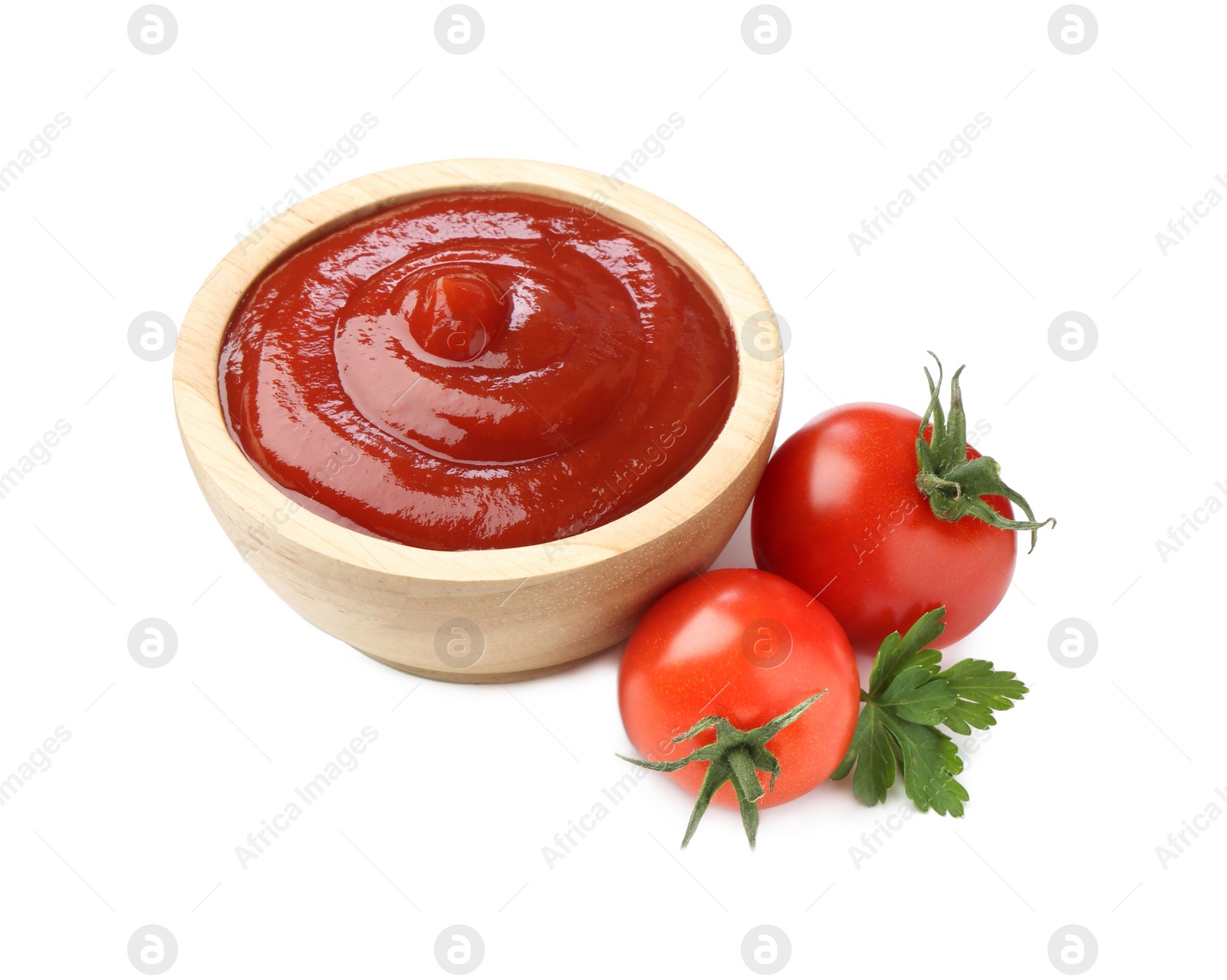 Photo of Tasty ketchup in wooden bowl, fresh tomatoes and parsley isolated on white