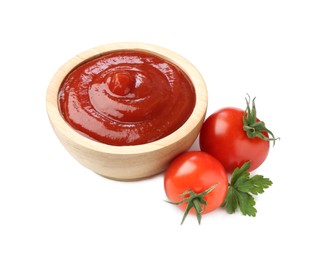 Photo of Tasty ketchup in wooden bowl, fresh tomatoes and parsley isolated on white