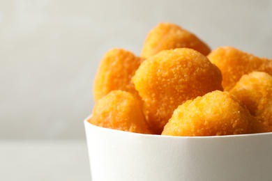 Delicious fried chicken nuggets on light grey background, closeup