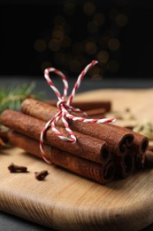 Photo of Cinnamon sticks and other spices on table against black background with blurred lights, closeup