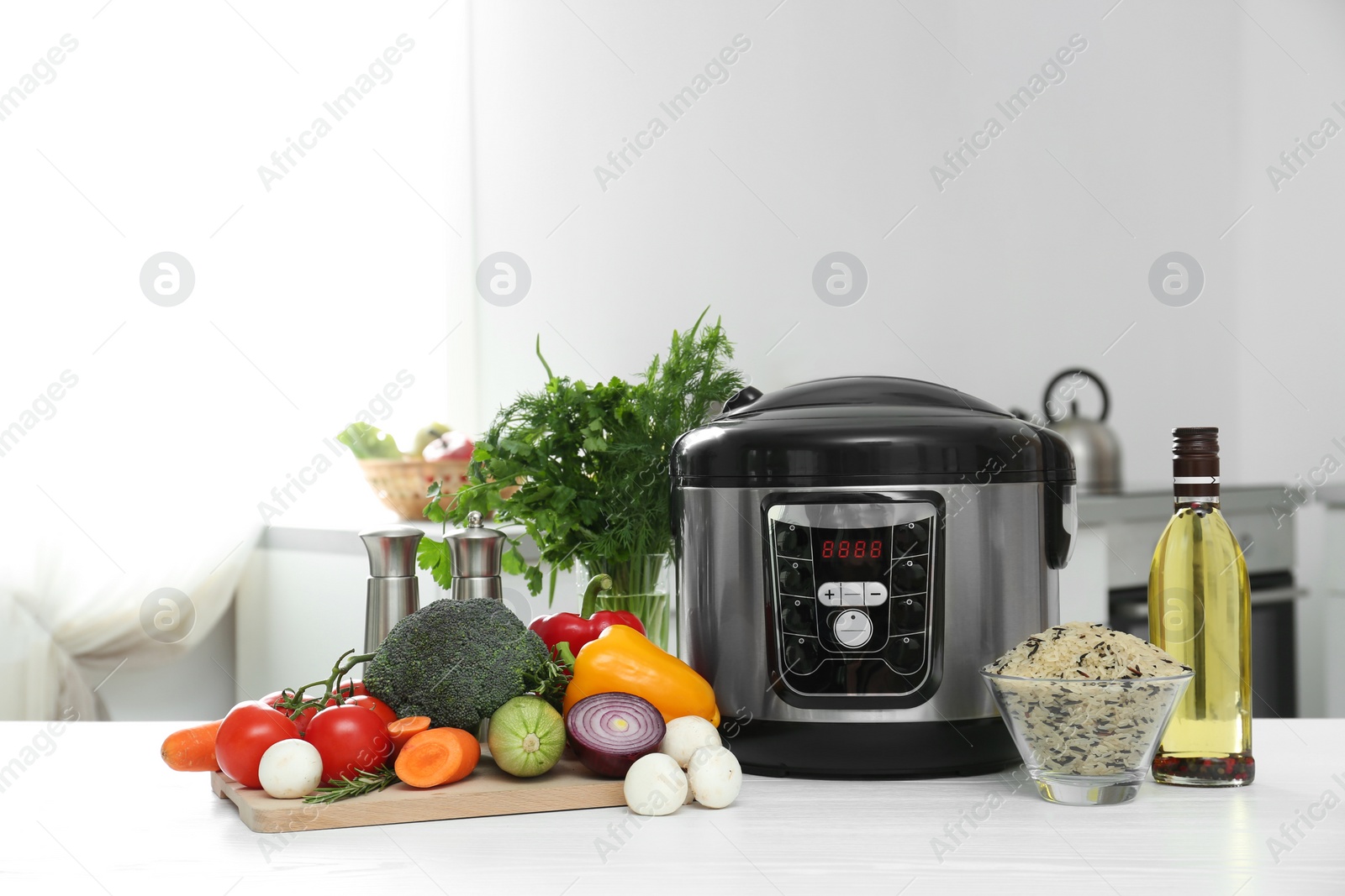 Photo of Modern multi cooker and products on table in kitchen. Space for text