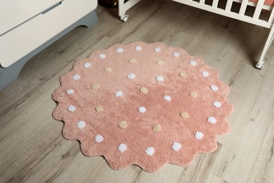 Round pink rug with polka dot pattern on wooden floor in baby's room