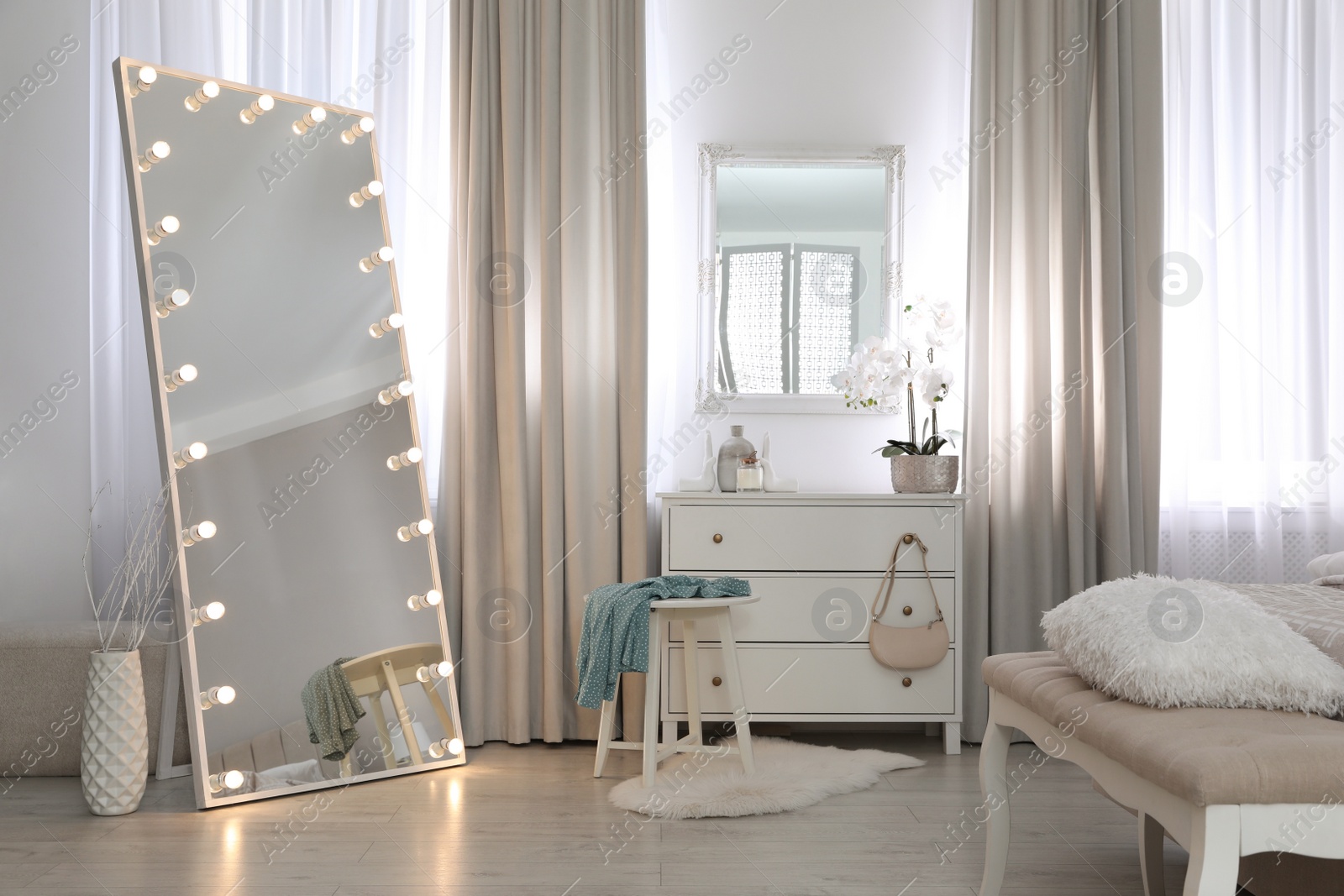 Photo of Large mirror with light bulbs and chest of drawers in bedroom. Interior design