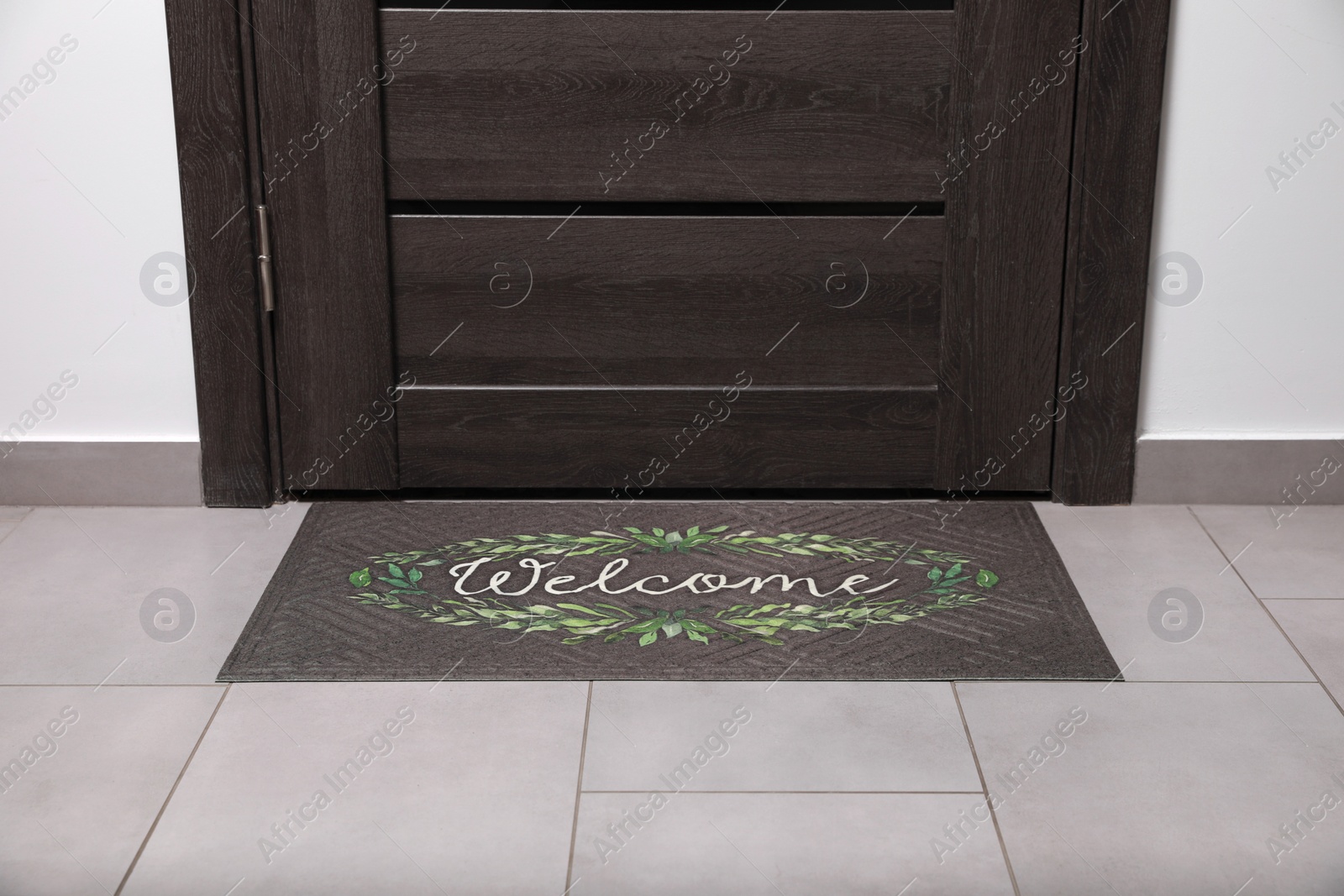 Photo of Beautiful doormat with word Welcome on floor near entrance