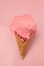 Photo of Melted ice cream in wafer cone on pink background, top view