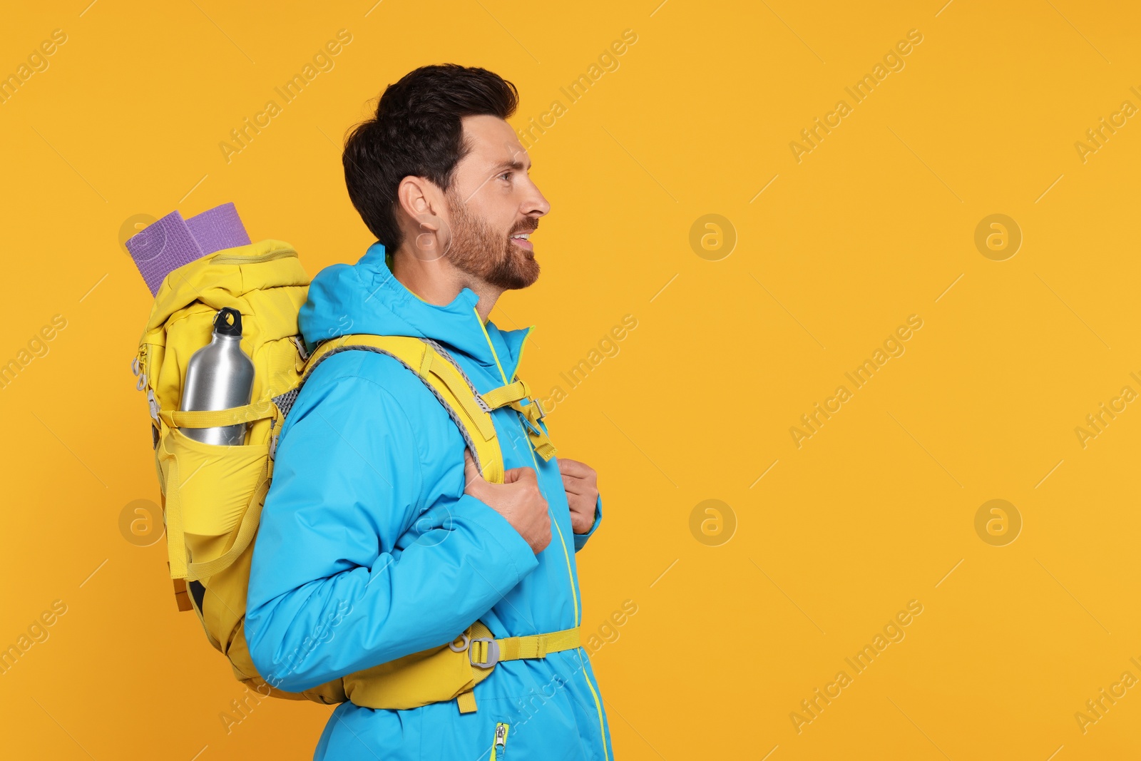 Photo of Man with backpack on orange background, space for text. Active tourism