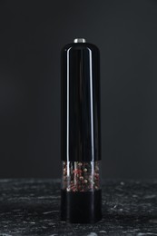 Photo of Pepper shaker on dark marble table, closeup
