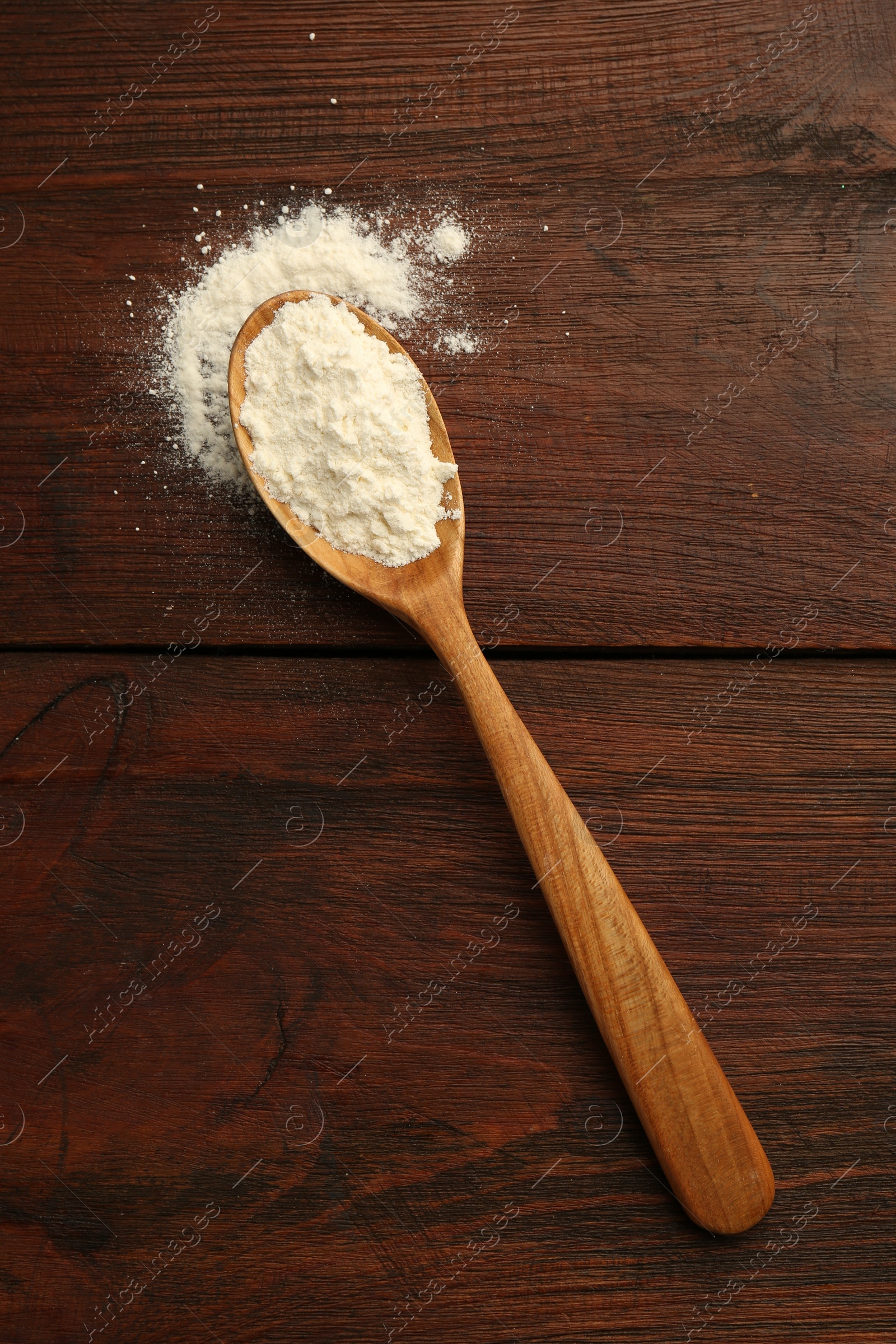 Photo of Baking powder in spoon on wooden table, top view