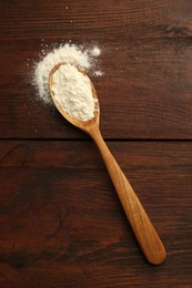 Baking powder in spoon on wooden table, top view