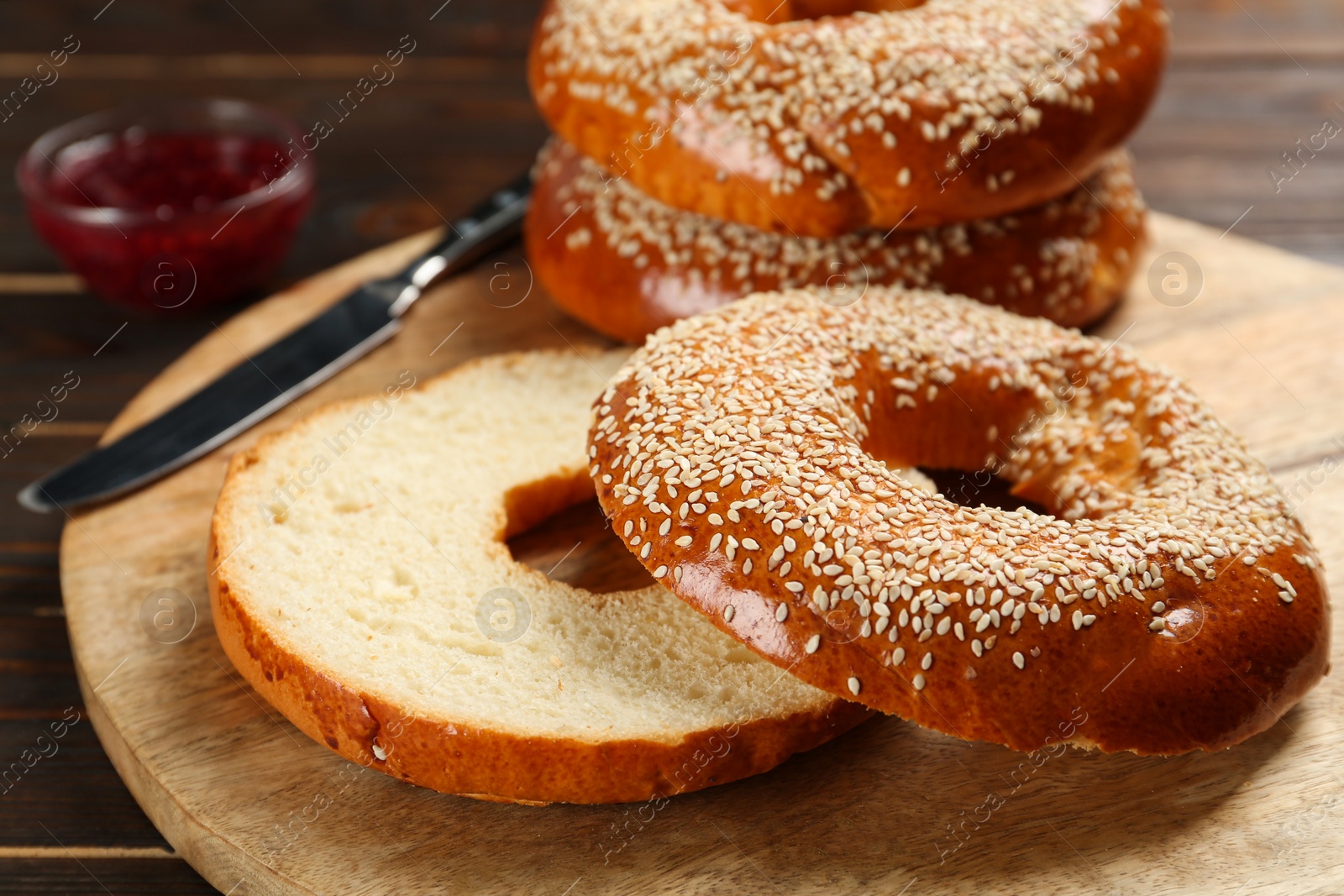 Photo of Delicious fresh bagels with sesame seeds on wooden table, closeup