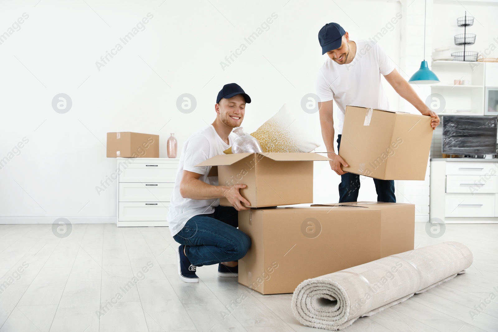 Photo of Moving service employees with cardboard boxes in room