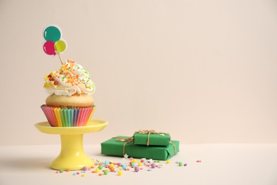 Photo of Birthday cupcake and gift boxes on beige background. Space for text