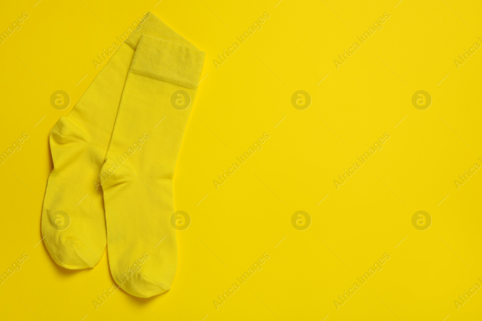Photo of Pair of new socks on yellow background, flat lay. Space for text