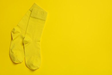 Pair of new socks on yellow background, flat lay. Space for text