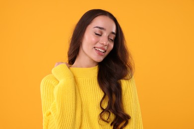 Photo of Beautiful young woman in stylish warm sweater on orange background