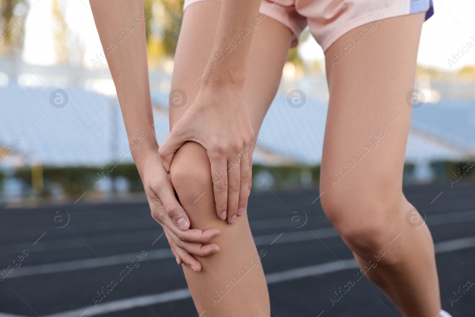 Photo of Young woman having knee problems at stadium, closeup