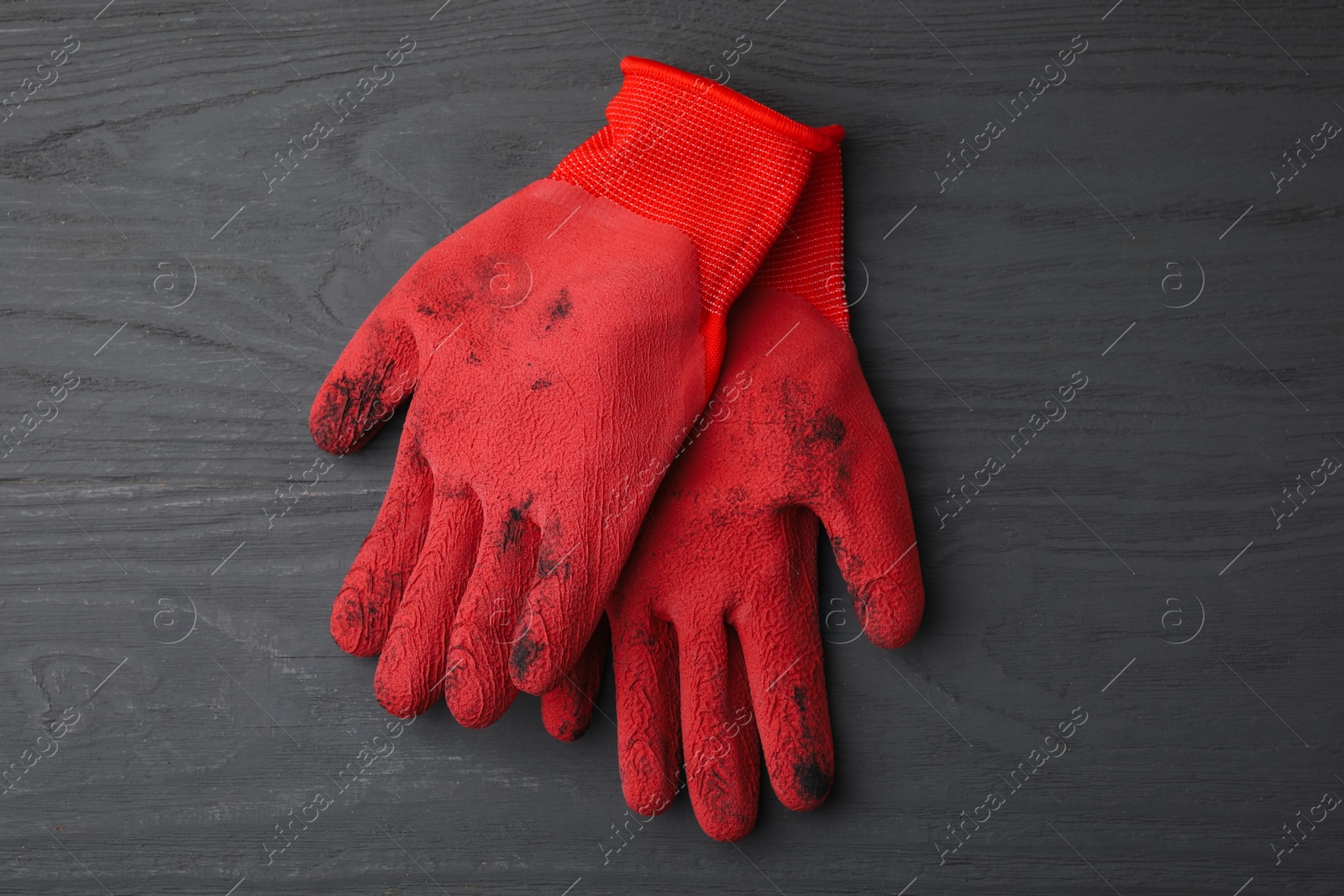 Photo of Pair of red gardening gloves on grey wooden table, top view