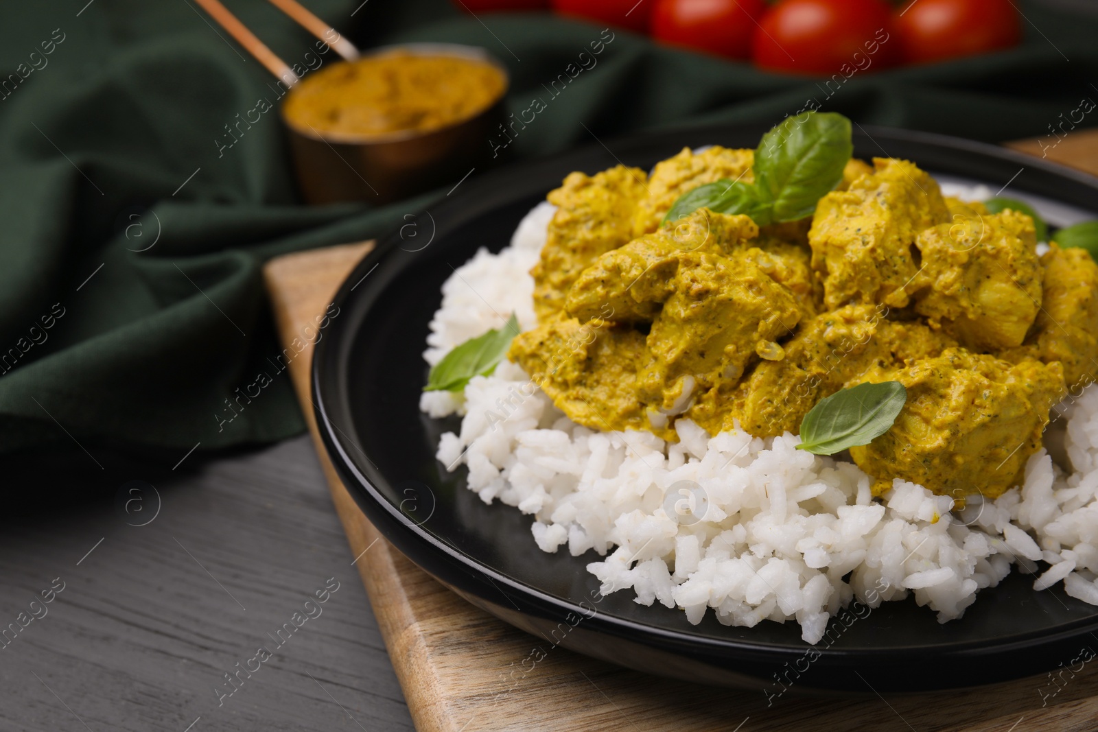 Photo of Delicious rice and chicken with curry sauce on grey wooden table, closeup. Space for text