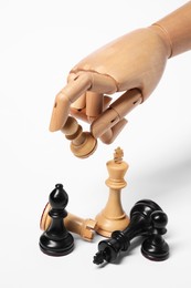 Robot holding pawn over other chess pieces on white background. Wooden hand representing artificial intelligence