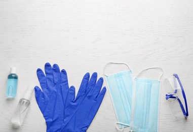 Photo of Flat lay composition with medical gloves, masks and hand sanitizers on white wooden background. Space for text