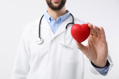 Photo of Doctor holding red heart on white background, closeup. Cardiology concept