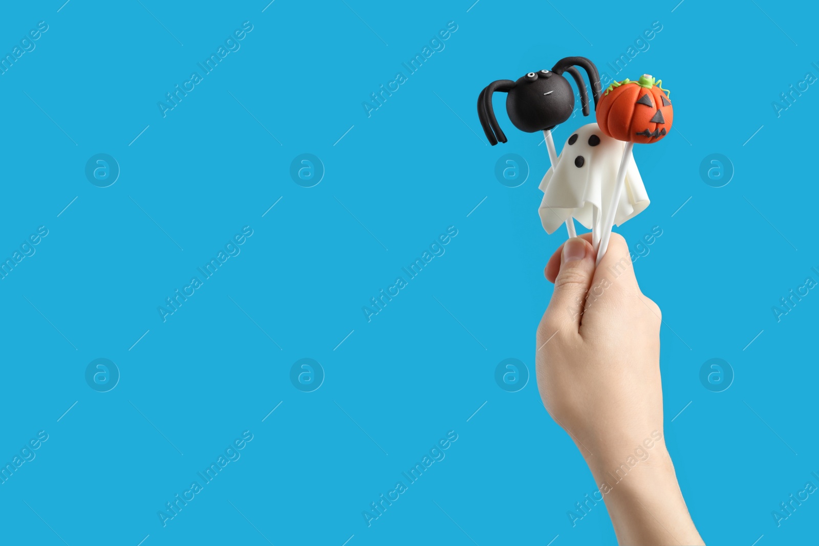 Photo of Woman with delicious cake pops and space for text on light blue background, closeup. Halloween celebration
