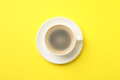 Photo of Aromatic coffee in cup on yellow background, top view