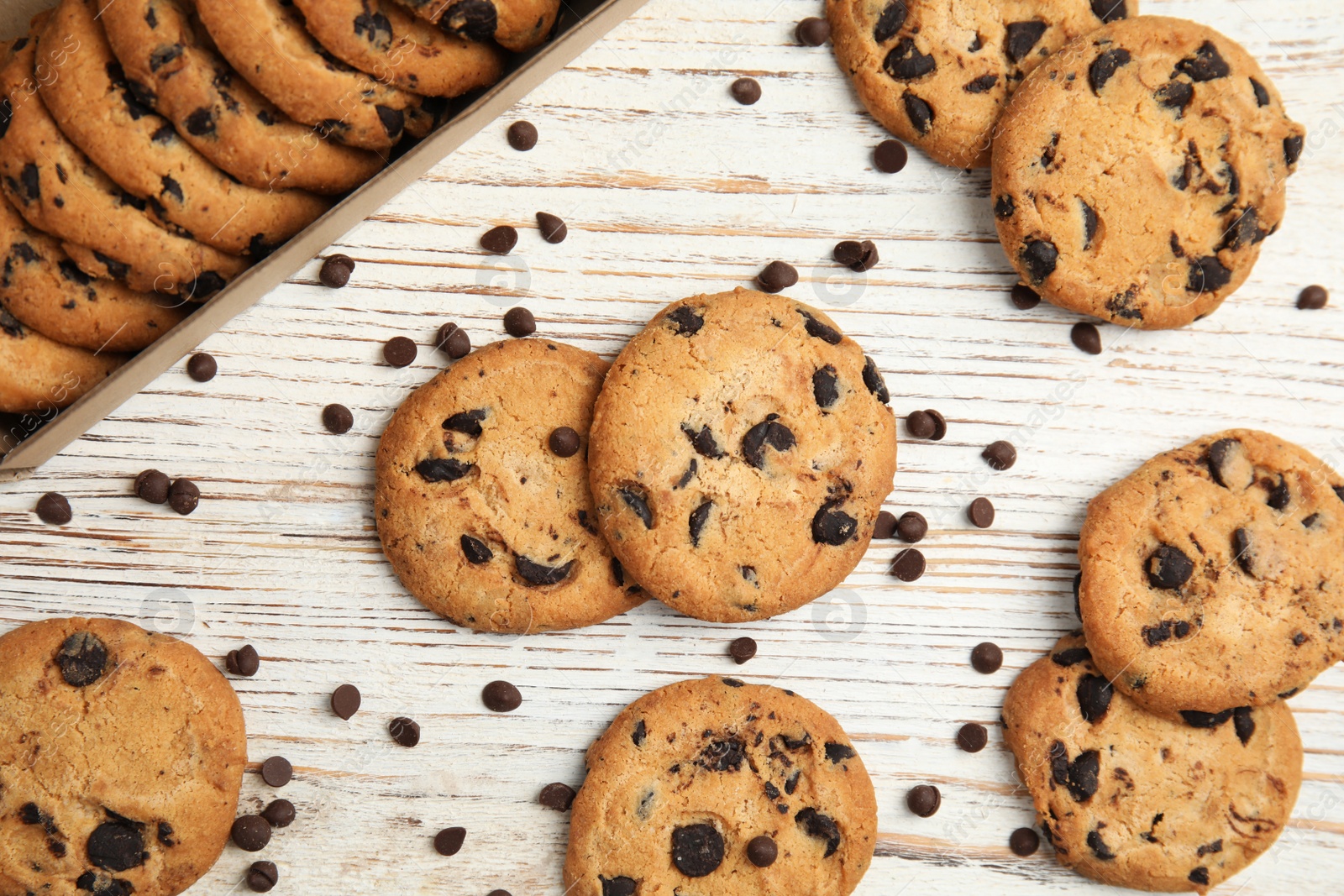 Photo of Delicious chocolate chip cookies on wooden table, flat lay