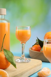 Delicious tangerine liqueur and fresh fruits on light blue table