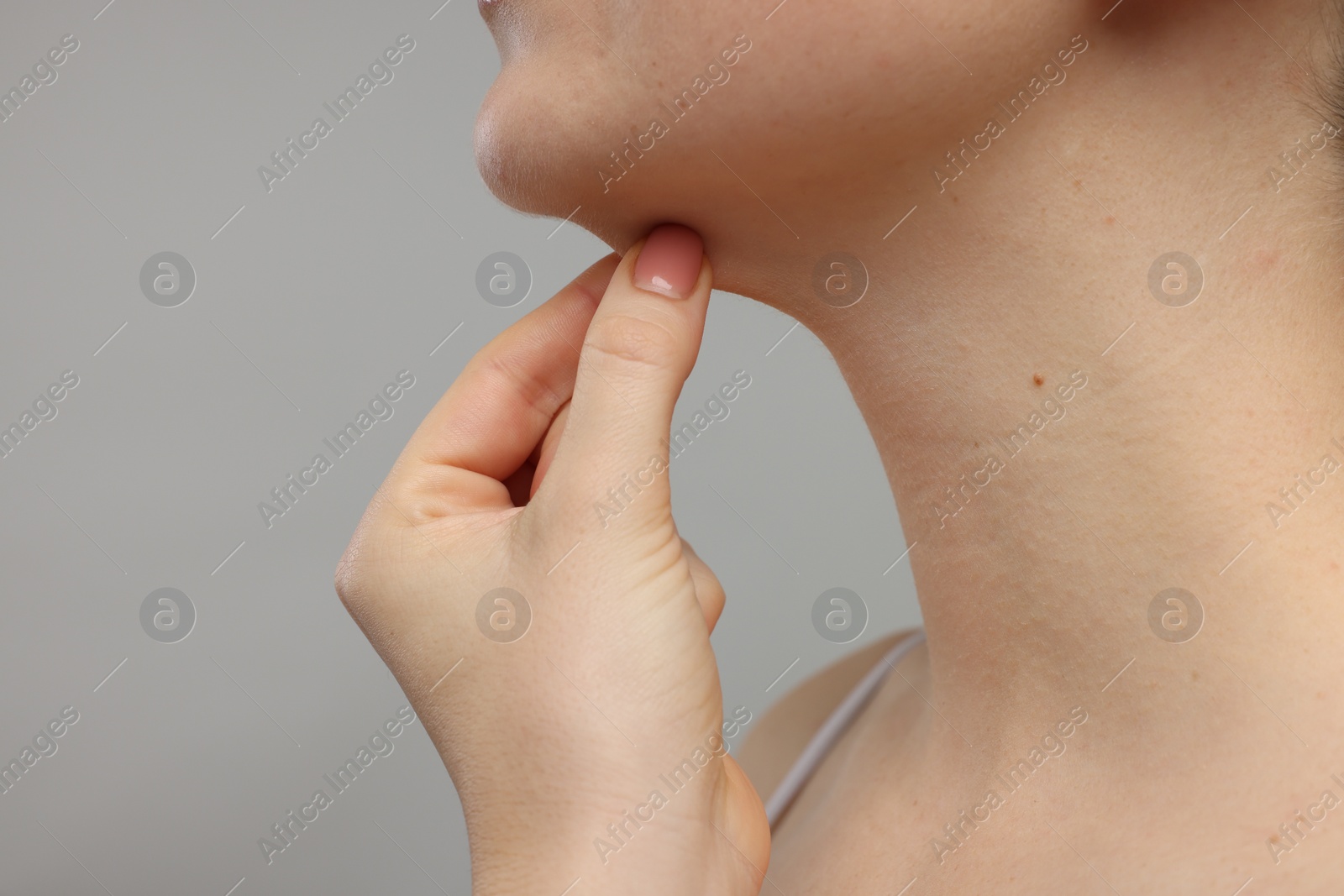 Photo of Woman touching her chin on grey background, closeup