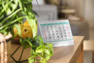 Photo of Paper calendar and plate with pears on wooden table indoors