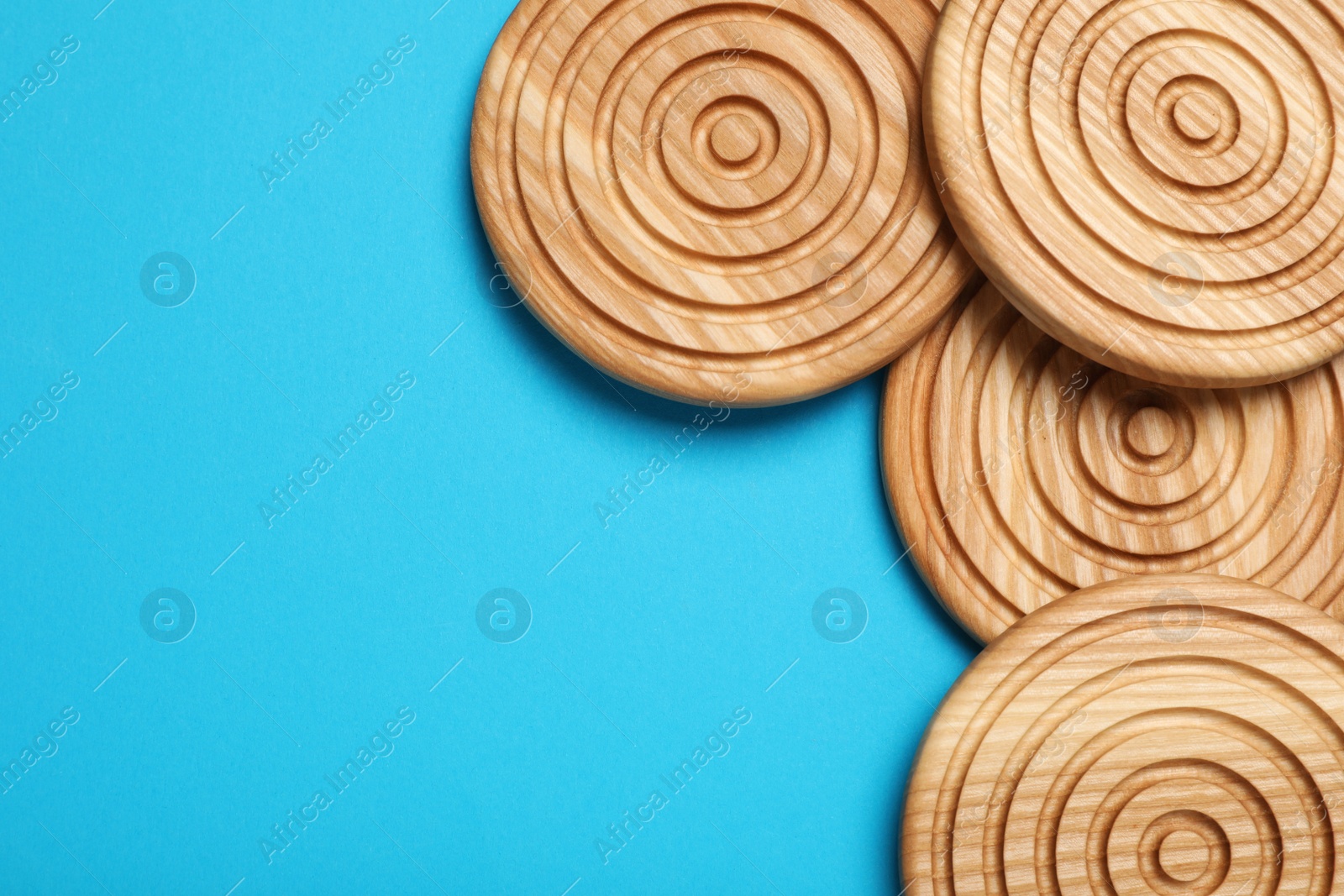 Photo of Stylish wooden cup coasters on light blue background, flat lay. Space for text