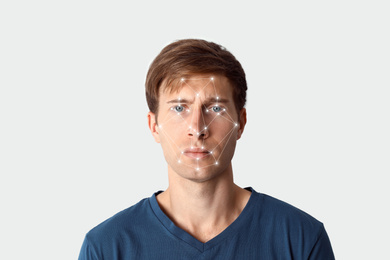Facial recognition system. Young man with digital biometric grid on white background