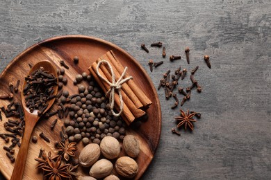 Photo of Different spices and nuts on gray textured table, top view. Space for text