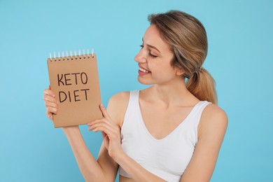 Photo of Woman holding notebook with phrase Keto Diet on light blue background