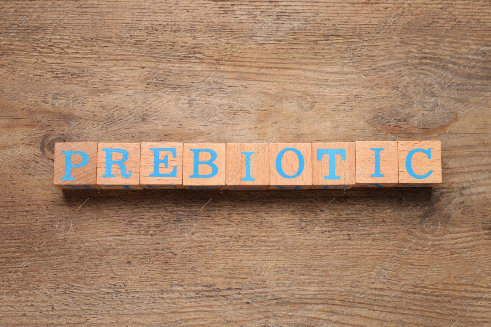 Photo of Wooden cubes with word Prebiotic on table, flat lay