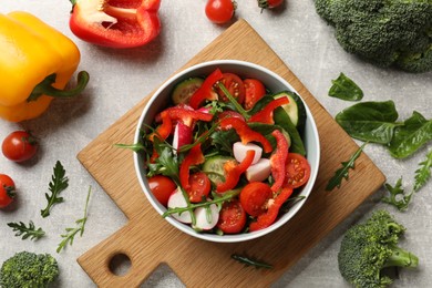 Tasty fresh vegetarian salad on light grey table, flat lay