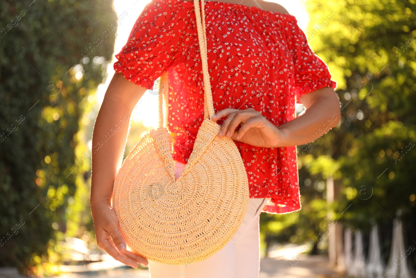 Photo of Young woman with stylish straw bag in park, closeup