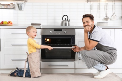 Young man and his son baking something in oven at home