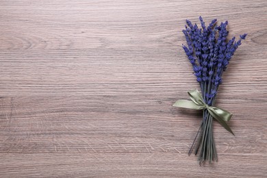 Photo of Bouquet of beautiful preserved lavender flowers on wooden table, top view. Space for text