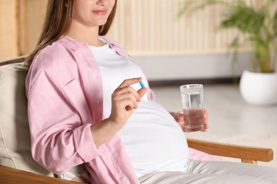 Photo of Pregnant woman taking pill at home, closeup