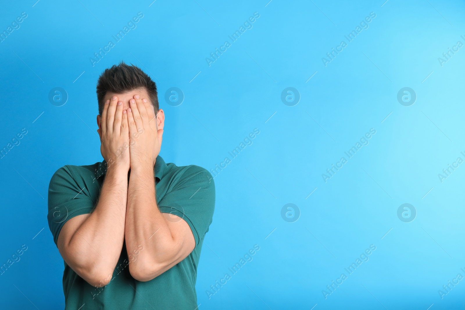 Photo of Man covering eyes while being blinded on blue background