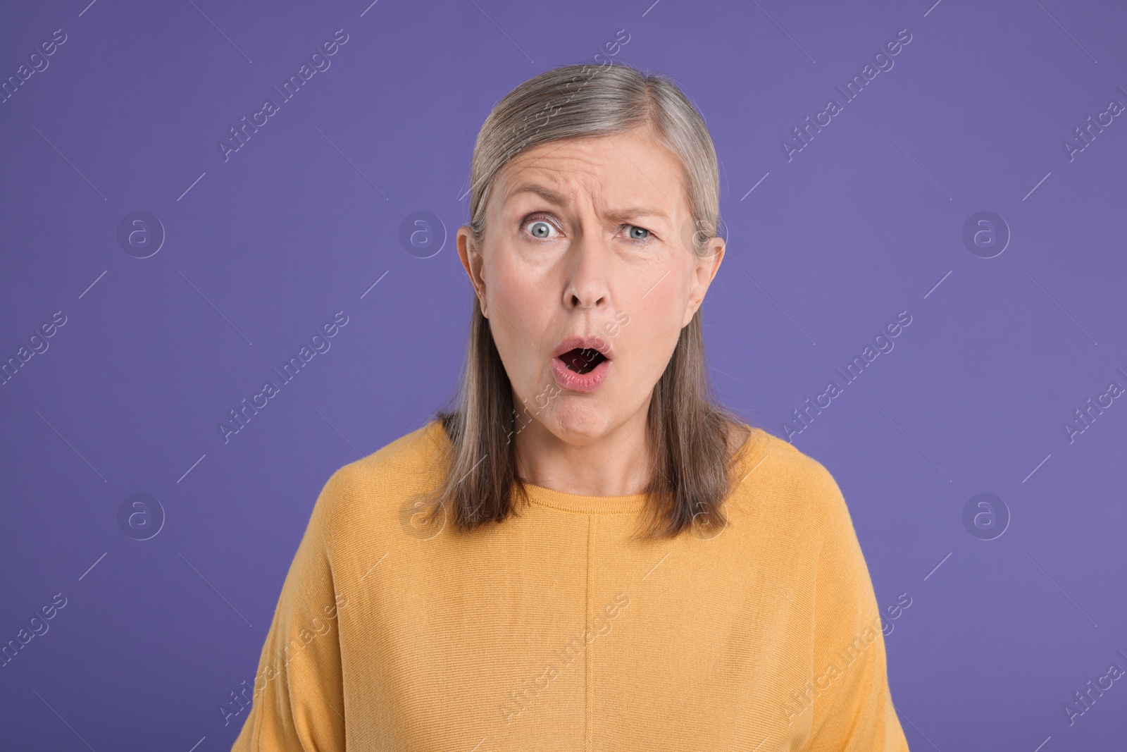 Photo of Portrait of surprised senior woman on violet background