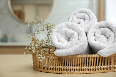 Photo of Fresh towels and plant on wooden table in bathroom, closeup