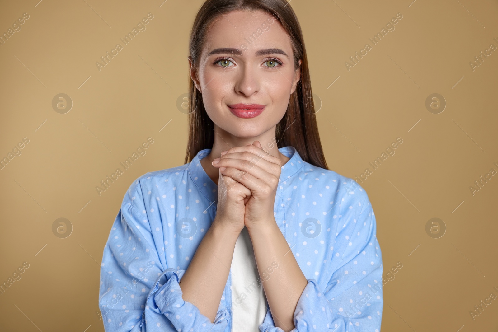 Photo of Woman with clasped hands praying on beige background