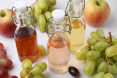 Photo of Different types of vinegar and ingredients on light tiled table, closeup